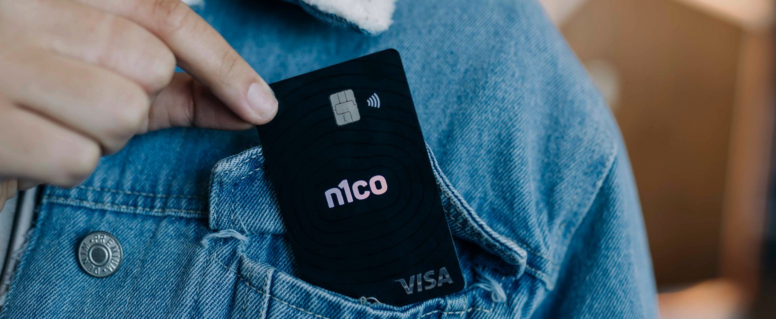 Mano que guarda una tarjeta negra de n1co en el bolsillo de una chaqueta de mezclilla