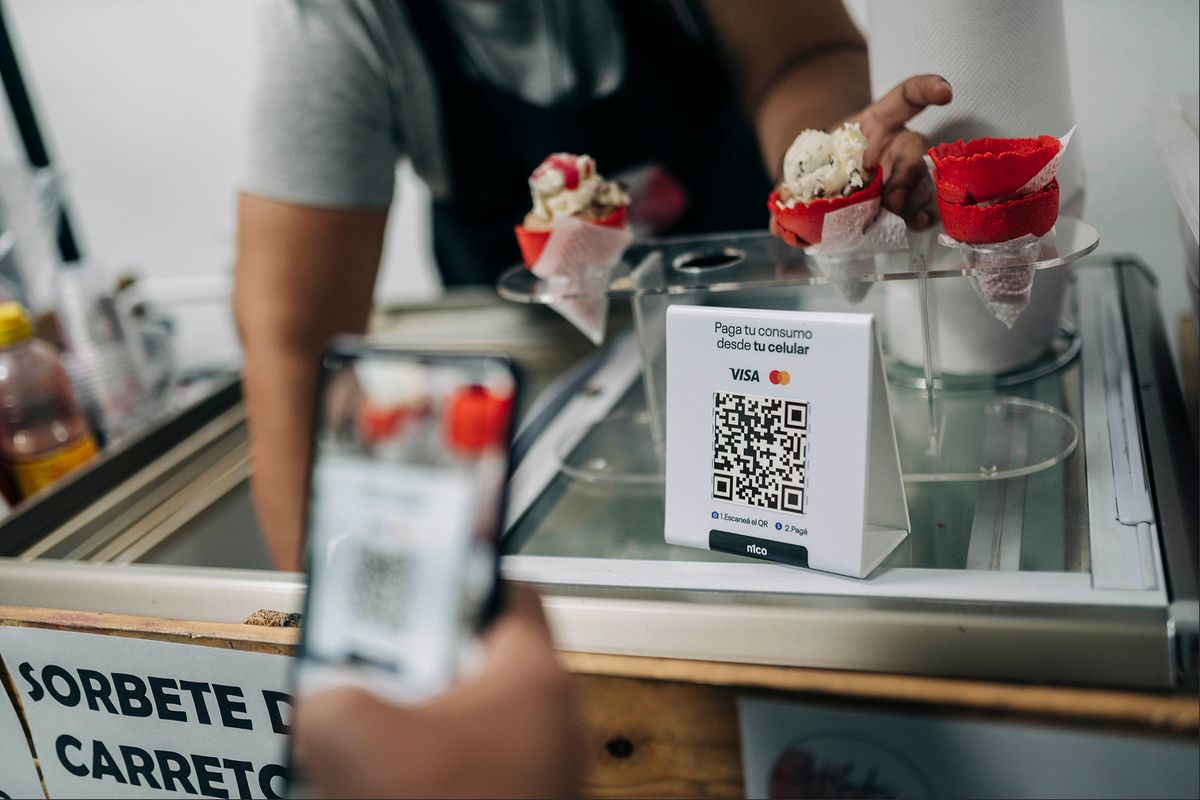 Cliente que escanea con su celular el código QR de pago de n1co en el mostrador de una heladería