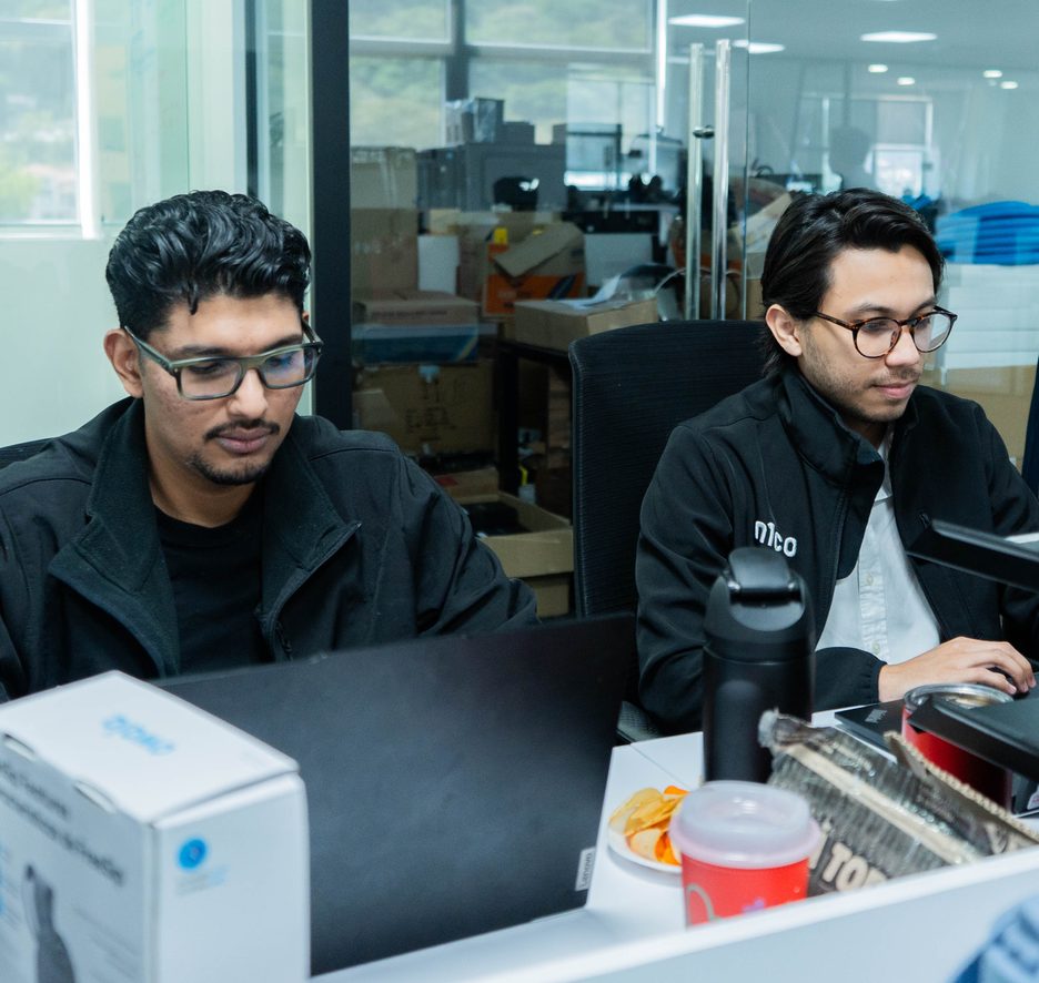 Dos personas del equipo de n1co trabajando en sus computadoras en la oficina