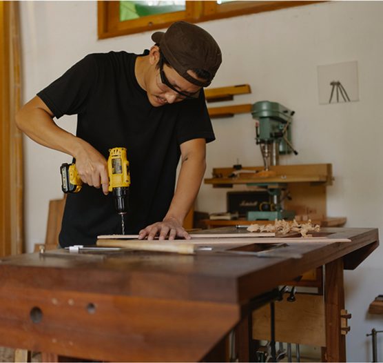 Carpintero que taladra una tabla en su taller