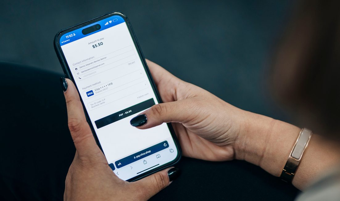 Manos con uñas oscuras que sostienen un teléfono con la app de n1co abierta en una pantalla de pago