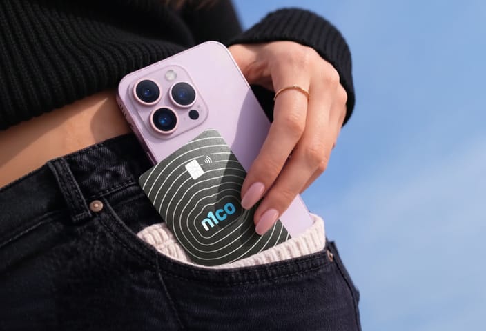 Mano que guarda en el bolsillo del pantalón un teléfono lila y una tarjeta n1co