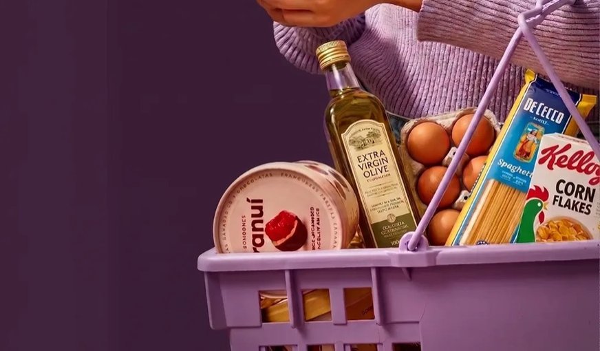 Canasta morada con aceite de oliva, huevos, pasta y una lata de atún