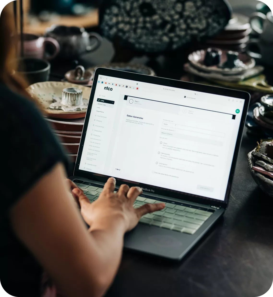 Persona que trabaja en una laptop con el portal de n1co abierto, en un taller de cerámica