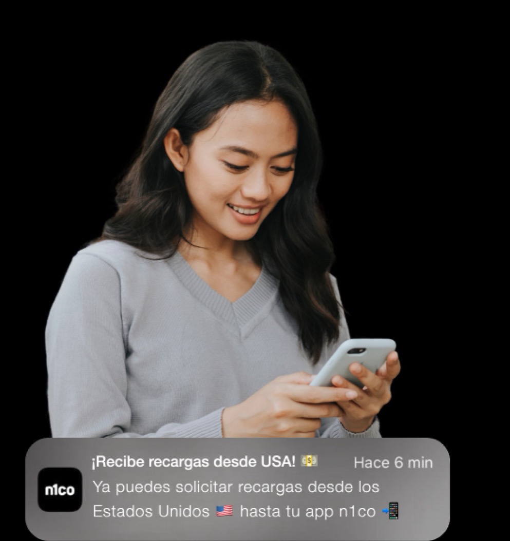 Mujer que sonríe mirando su teléfono, con una notificación de recarga de n1co