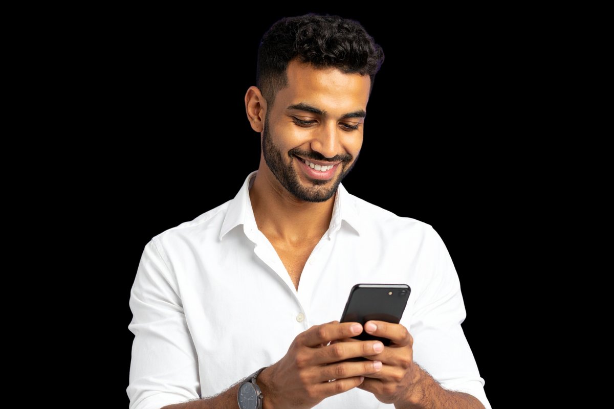 Hombre sonriente con camisa blanca que mira su teléfono