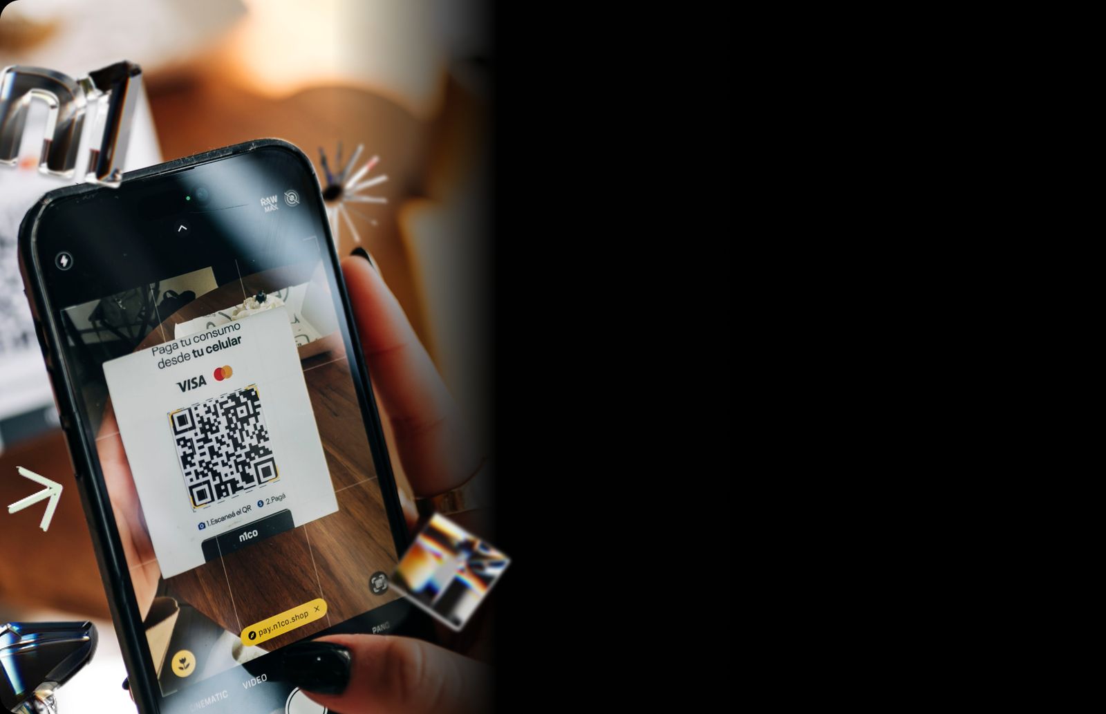 Mano que sostiene un celular y escanea el código QR de pago de n1co de una mesa